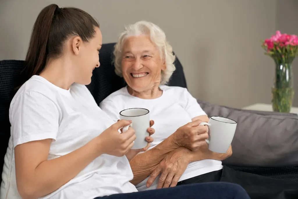 A carer sharing a cup of tea with an older woman at home in Middlesex